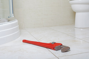 Plumbing wrench on the bathroom ceramic floor.