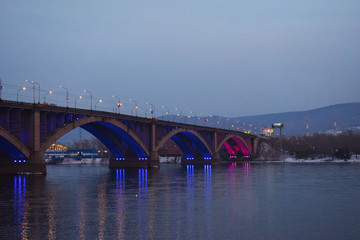 Fototapeta na wymiar Sightseeing in Krasnoyarsk. Illuminated bridge. yenisei river. The city lights at night. 