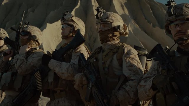 Close-up Moving Shot Group of Fully Equipped Soldiers Standing in a Line in the Desert. Paratroopers Ready for the Mission in Desert Region