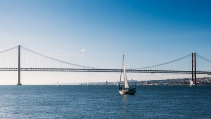 Sailboats with white sails on the Tagus River, 25 of April Bridge, Lisbon, Portugal