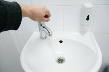 Man hand gold the water tap. Water saving closing tap.