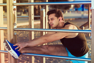 Male athlete stretching on outdoor fitness station