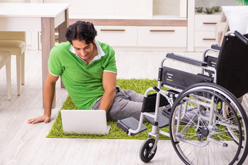 Young handsome man in wheelchair at home 