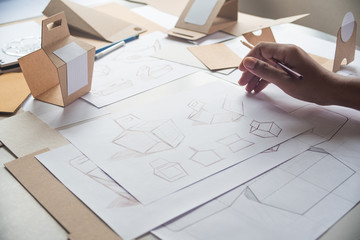 Designer sketching drawing design Brown craft cardboard paper product eco packaging mockup box development template package branding Label . designer studio concept .