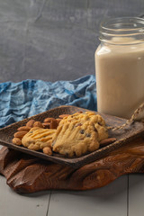 close up of almond cookies on wooden plate and milk