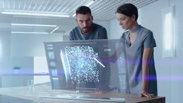 Futuristic Concept: Male and Female Computer Engineers Talk While Working on the Holographic Display Computer. Screen Shows Interactive Neural Network, Artificial Intelligence Project, User Interface