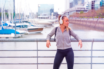 An athletic woman listening to music next to the bridge railing