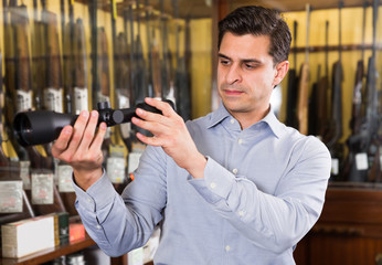 Man owner of hunting store checking optical sights