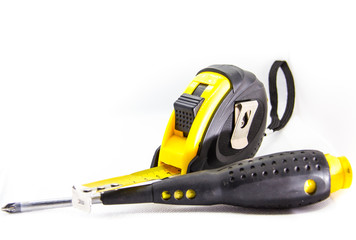 construction tool measuring tape next to screwdriver on white background
