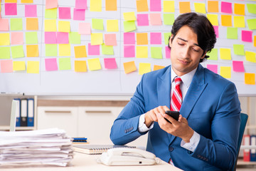 Young handsome employee with many conflicting priorities 