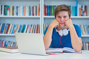 student preparing exam and learning lessons in school library, making research on laptop and browse internet 