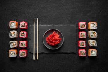 Sushi rolls, maki, nigiri on black stone slate on dark background copy space