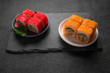 Sushi rolls, maki, nigiri on black stone slate on dark background copy space