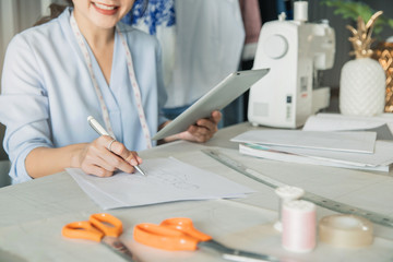 Young female fashion designer working on her designs in the studio. Fashion designer drawing sketches for new collection. Beautiful fashion woman designer drawing in studio .