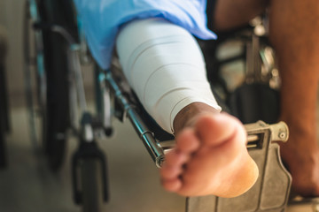 Man with a broken leg sits in a wheelchair in hospital room,copy space.