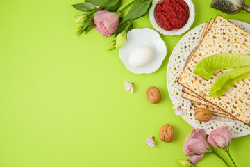 Jewish holiday Passover background with matzo, seder plate and spring flowers.