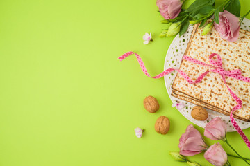 Jewish holiday Passover background with matzo, seder plate and spring flowers.