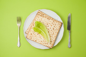 Jewish holiday Passover seder dinner table setting with matzo on plate.
