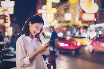 Women use smartphone at night on city shopping street, and use the map application in  navigation.