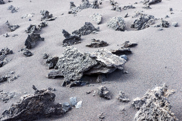 Pointed stones on gray sand. Sand and stone background