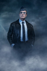 Vintage world war 2 pilot in sunglasses under dark sky.