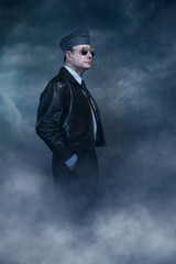 Vintage world war 2 pilot in sunglasses under dark sky. Side view.