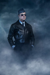 Vintage world war 2 pilot in sunglasses under dark sky.
