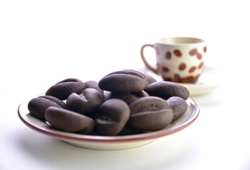 chocolate coffee beans in a mug on a saucer, white background