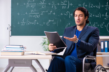 Young handsome man in wheelchair in front of chalkboard 