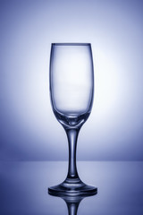 Empty wine glass on a blue background with a bright spot in the center