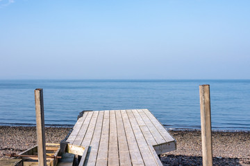Blue Sky Blue Sea and an Old Rickety Slanted Jetty on a Stoney Beach in Largs on the West Coast of Scotland.
