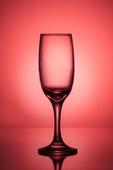 Empty wine glass on a red background with a bright spot in the center