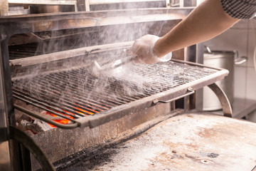 food, crafting and sausages concept - man cooking sausages on a flat grill