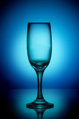 Empty wine glass on a blue background with a bright spot in the center