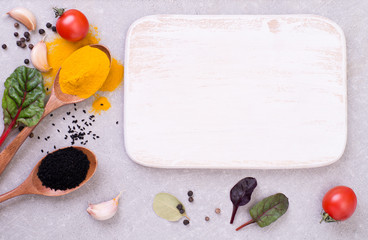 Naklejka na ściany i meble Aromatic spices on a gray background with a white wooden empty small board