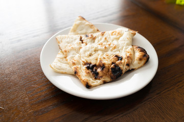 Pieces of Indian Nann bread on white plate