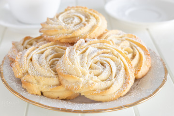 Shortbread whipped nuts cookies on white plate. White wooden background. Copy space. Close up.