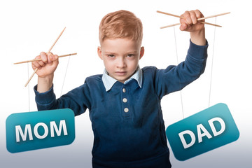child manipulates the parents. the boy is holding puppets with the words mom and dad on a white...