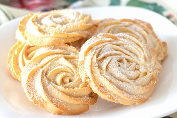 Shortbread whipped nuts cookies on white plate. White wooden background. Copy space. Close up.