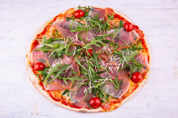 Arugula and cherry tomatoes Proshutto pizza, is served with tomato sauce and a carbonate