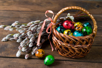 Wicker basket with Easter eggs and willow twigs bouquet