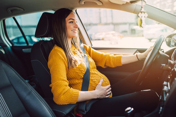Pregnant woman driving with safety belt on in the car.