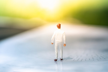 Miniature people standing on narrow street with nature backgrounds.