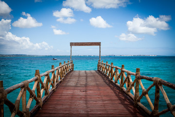 Lovely wooden pier leading to turquoise Indian Ocean at Prison Island near Zanzibar, Tanzania. Romantic and inspiration view on a sunny and lovely day
