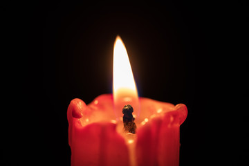 Red candle on black background, flame extreme closeup