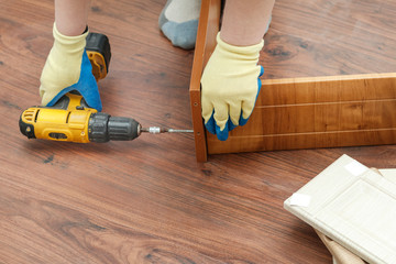 is the process of assembling furniture from chipboard. in the hands of a rechargeable screwdriver...