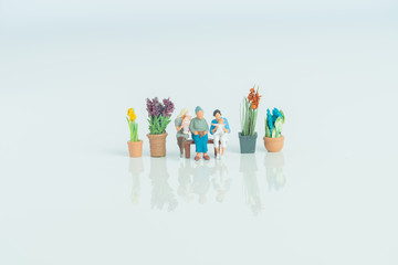 Fototapeta premium Miniature figurines - 3 generations of people on white background.