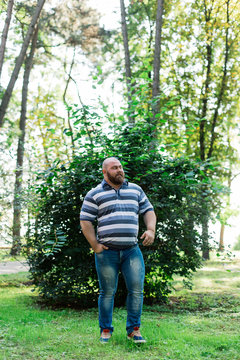 Fat man in the park looks into the frame, a portrait of a man with excess weight.