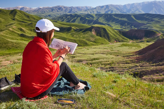 Girl draws on nature spring landscape. Painting outdoors. Kazakhstan. Mountain landscape