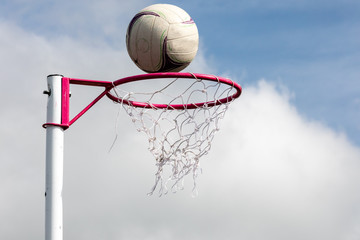 Netball post with ball about to go through the net